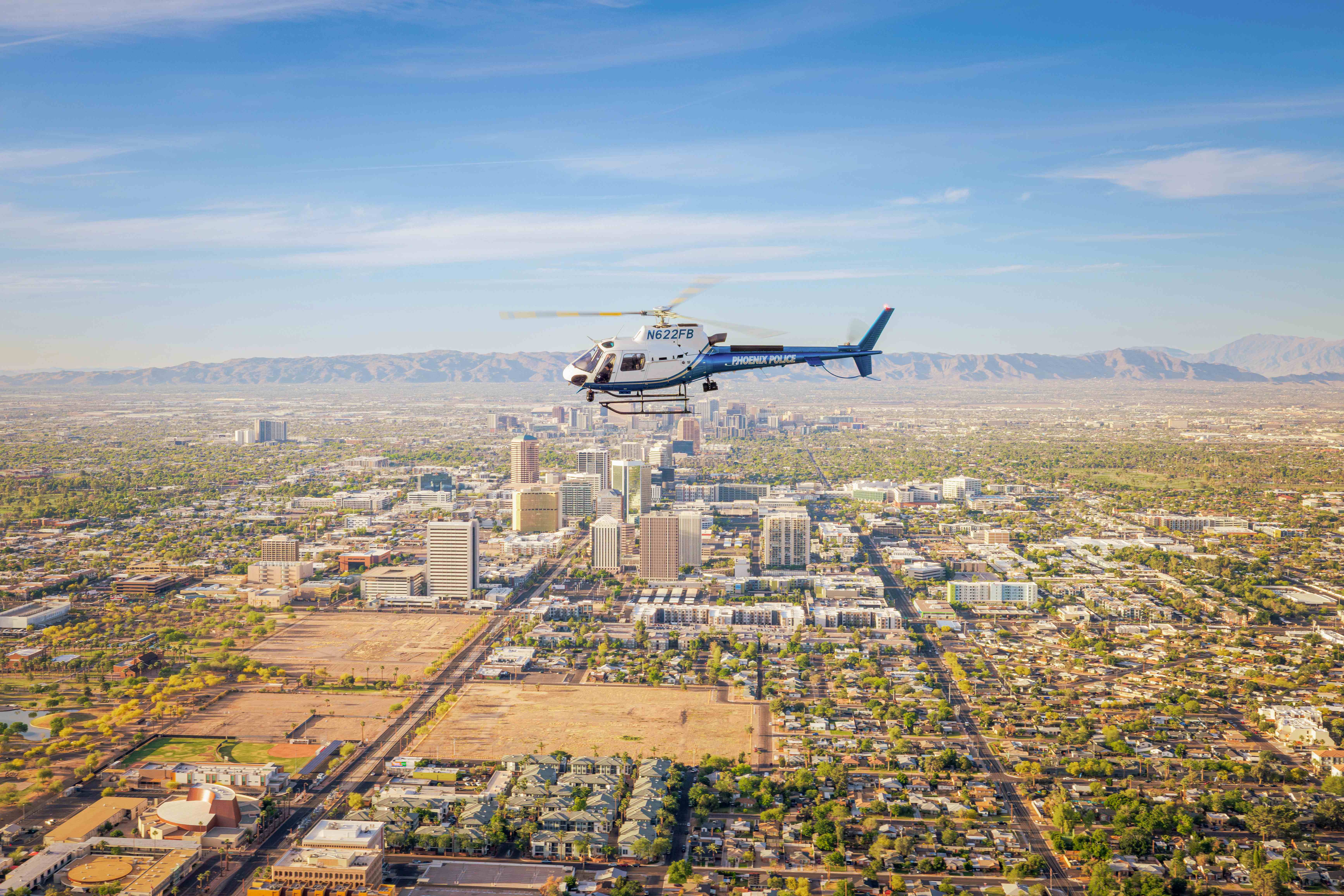 Phoenix Police Airbus H125 helicopter in level flight over downtown Phoenix with South Mountain in background Phoenix Police Airbus H125 helicopter flying over downtown Phoenix with South Mountain in background
